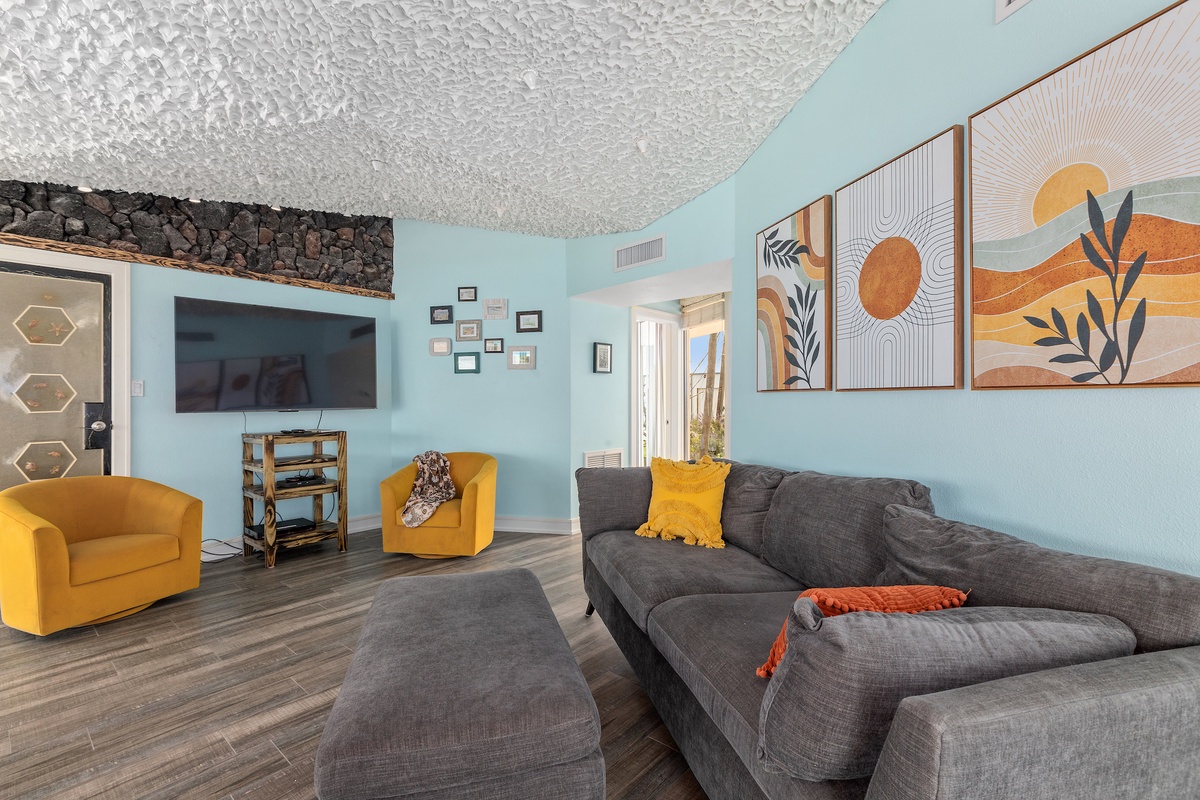 Unwind in your vibrant living space with plush gray seating, bold yellow accents, and cheerful artwork that creates the perfect atmosphere for relaxation.