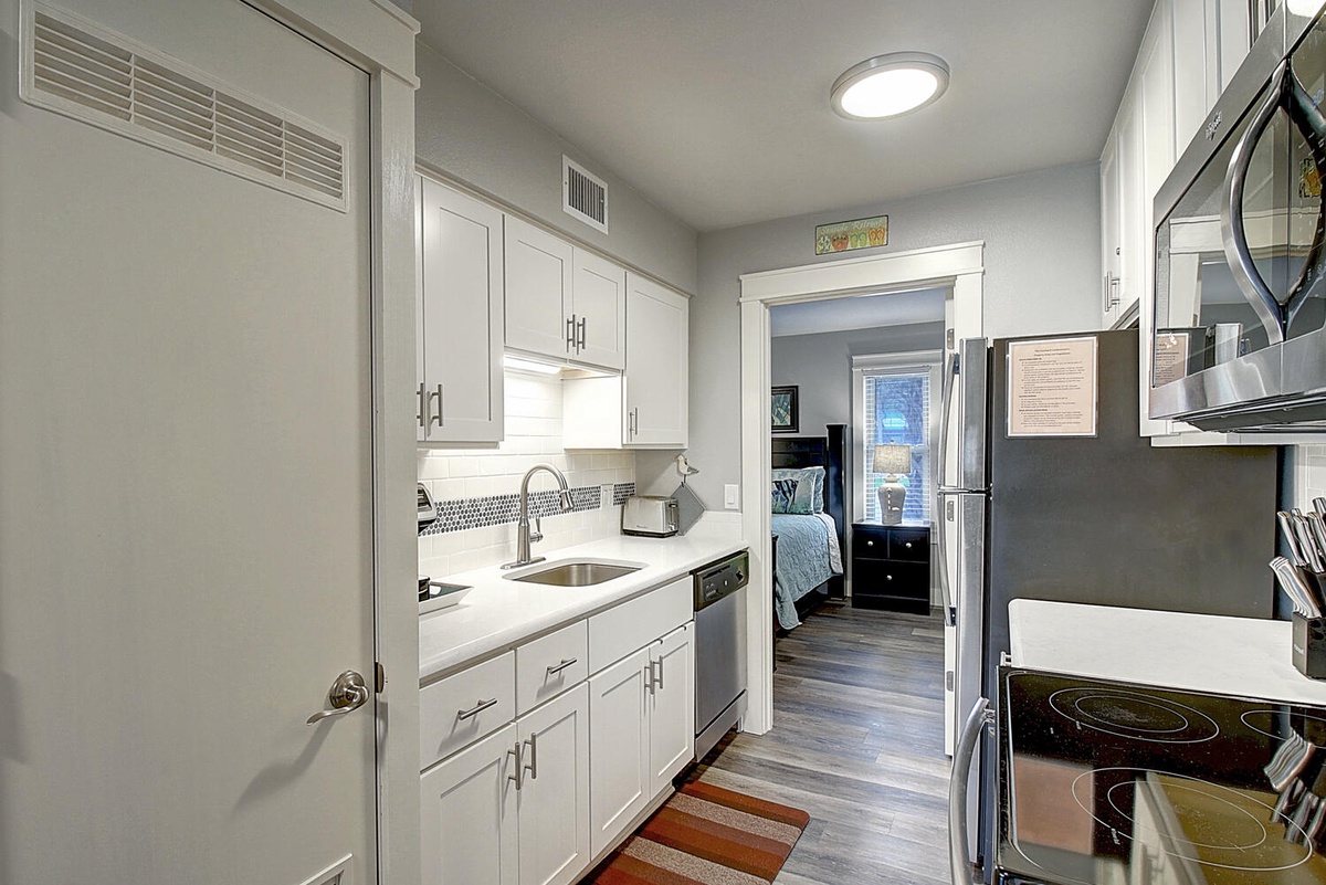 Your fully equipped galley kitchen features crisp white cabinets, modern appliances, and gleaming countertops—everything you need to prepare meals during your stay.