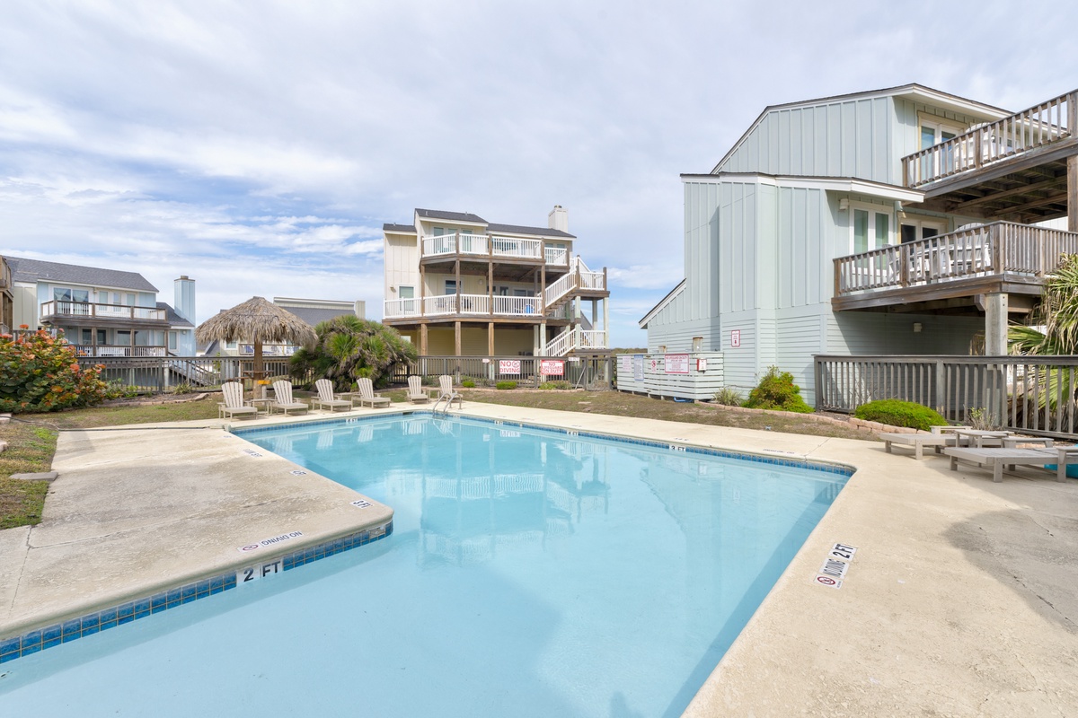 Beachfront community pool area with coastal homes and palm trees creating a relaxing vacation atmosphere.