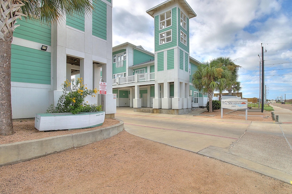 Modern coastal architecture with distinctive turquoise and white exterior, complete with tropical palm landscaping and convenient entrance access.