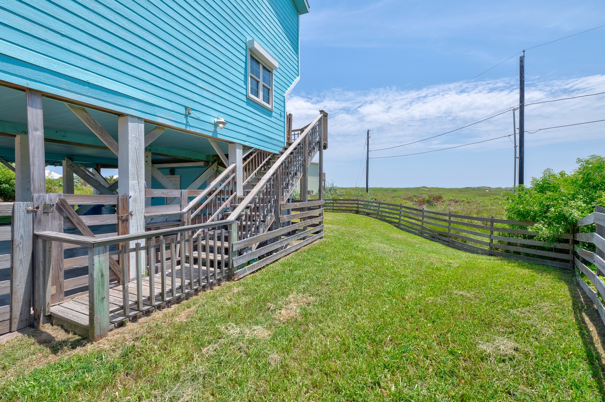 Grassy side yard with coastal views and convenient stairs leading to the home.