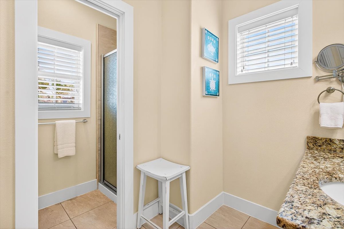 Step into your bright, pristine bathroom where morning routines become moments of calm with beautiful granite counters and coastal artwork.