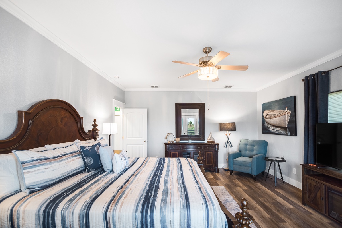 Drift off in your spacious master suite with plush bedding, cozy reading chair, and gentle ceiling fan for perfect comfort.