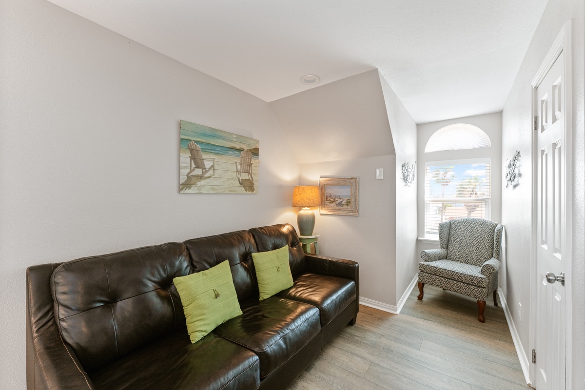 Unwind on the plush leather sofa with beach-themed artwork setting a coastal mood, while your reading nook awaits by the sunny window.