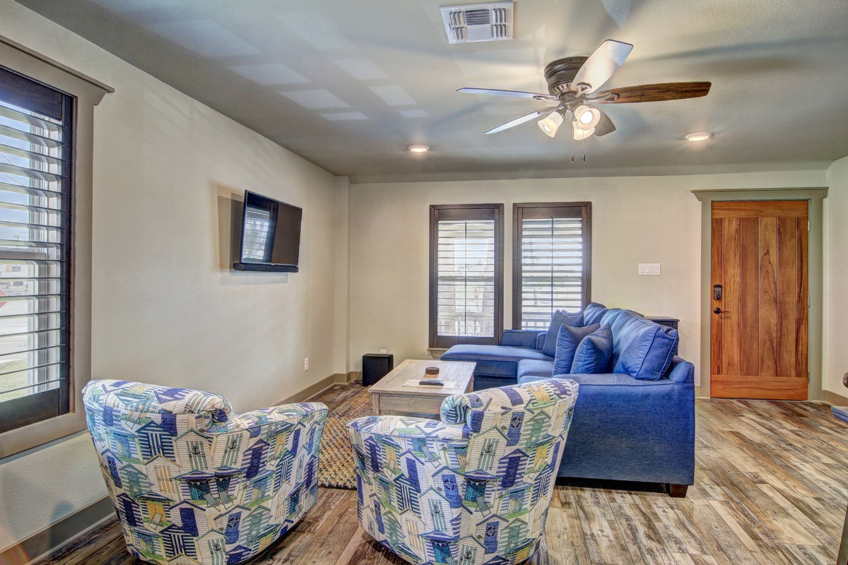Unwind in your spacious living room with plush seating, natural light streaming through plantation shutters, and gentle ceiling fan keeping you comfortable.