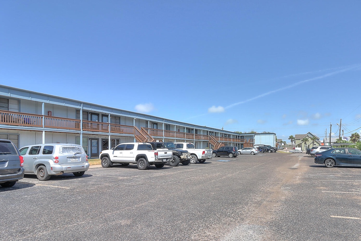 Two-story motel with convenient parking directly outside room doors under clear blue skies.