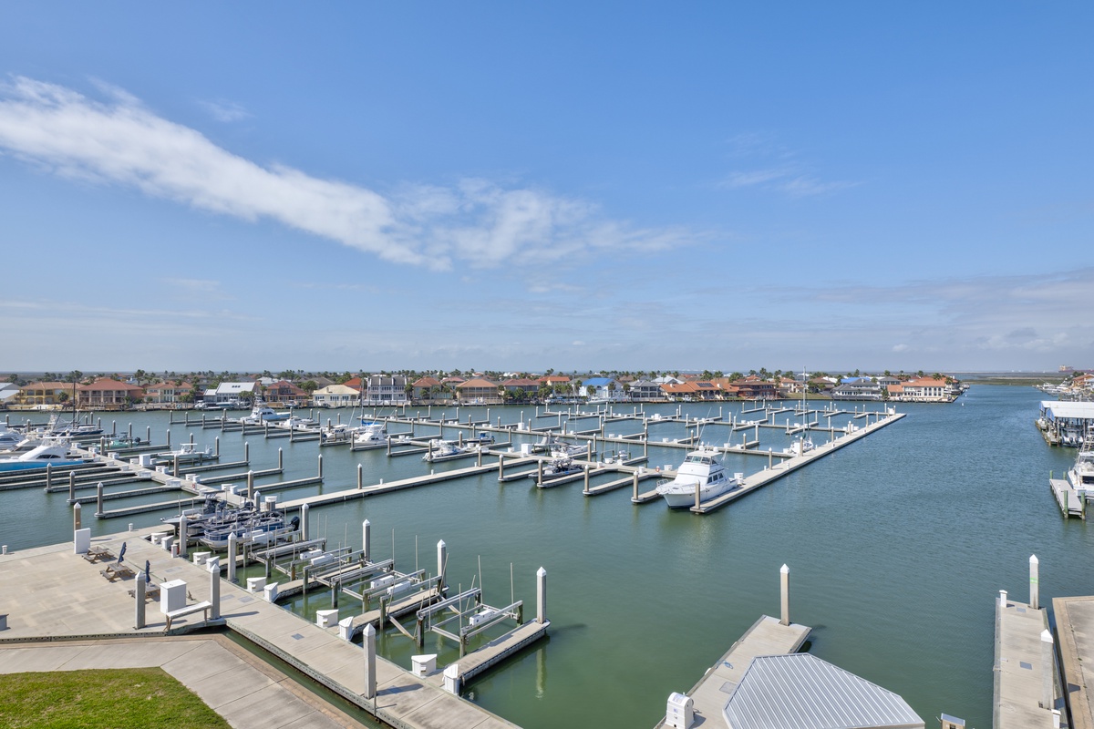 Expansive marina with pristine boat slips stretches across turquoise waters, framed by charming waterfront community beneath brilliant blue skies.