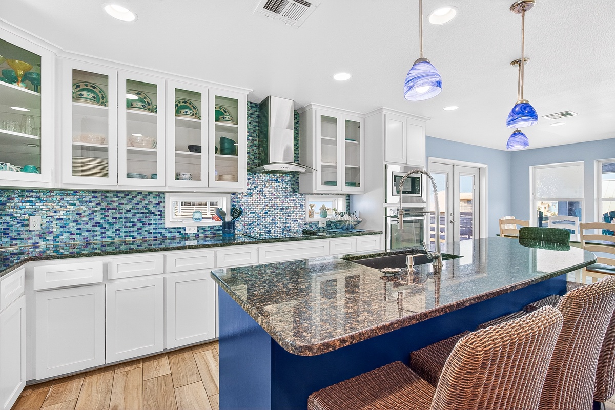 Your gourmet kitchen features granite counters, ocean-blue mosaic backsplash, and stainless steel appliances for memorable vacation meals.