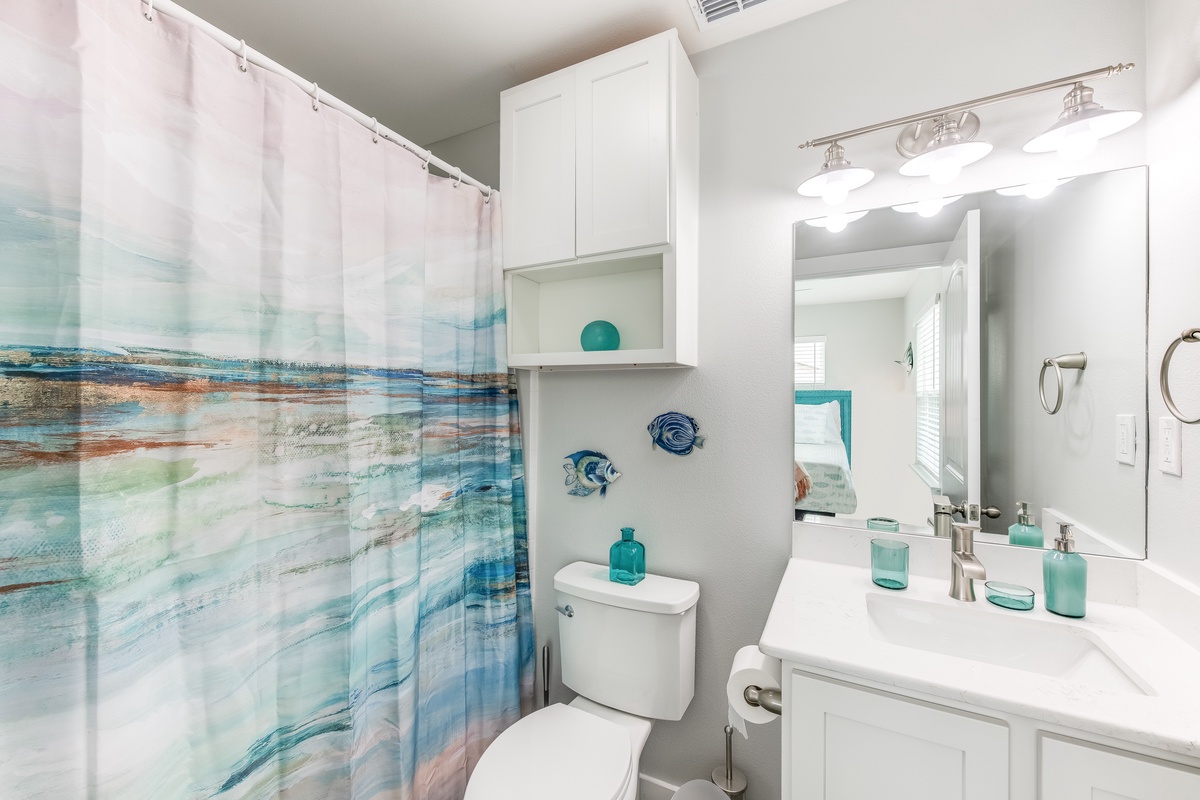 Refresh in your beautifully appointed bathroom with ocean-themed touches, white cabinetry, and modern amenities for your comfort.