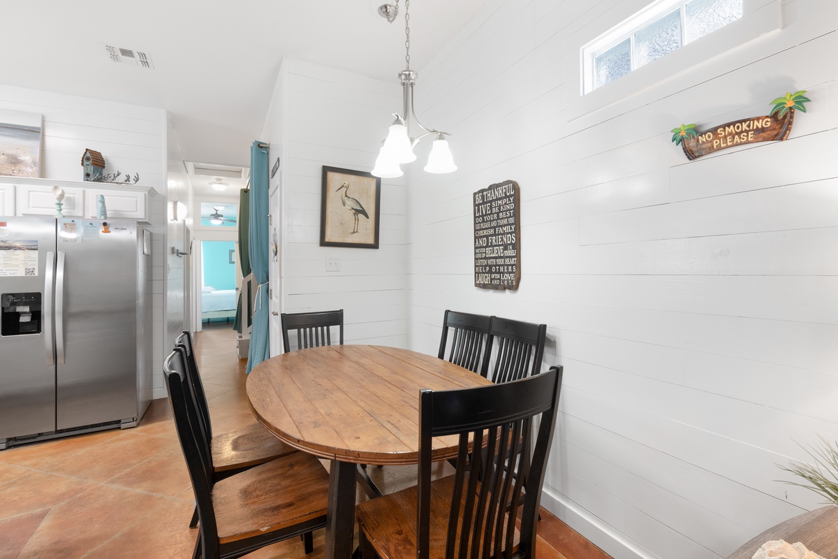 Gather around your cozy dining table where warm wood meets coastal charm, perfect for morning coffee or evening meals together.