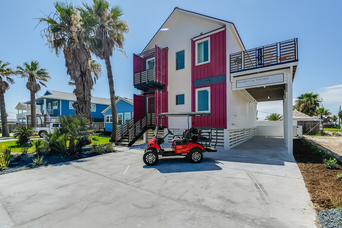 Modern beachside property featuring distinctive red and white architecture with convenient covered parking.