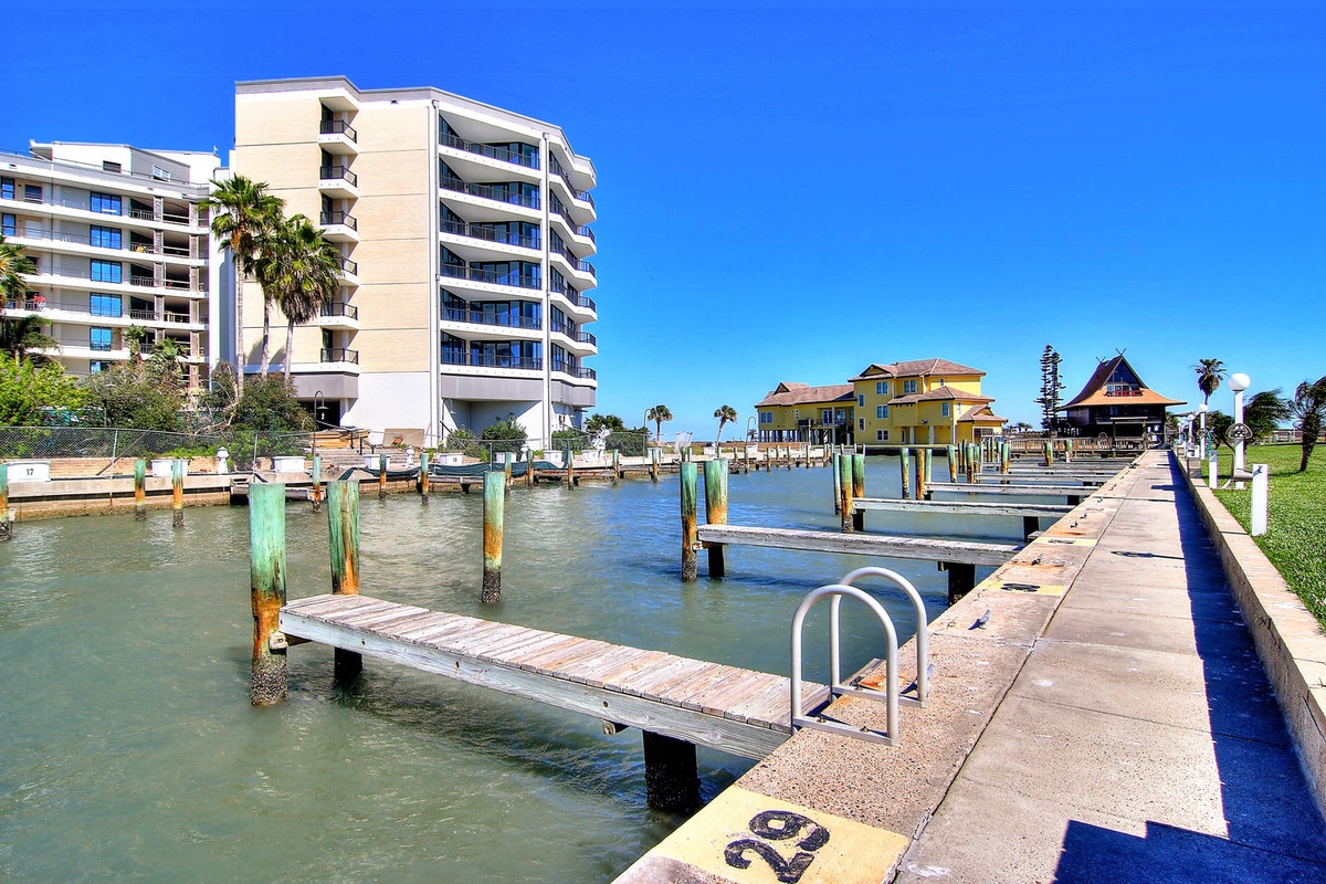 Waterfront marina with boat docks stretching into calm bay waters beneath bright blue Florida skies.