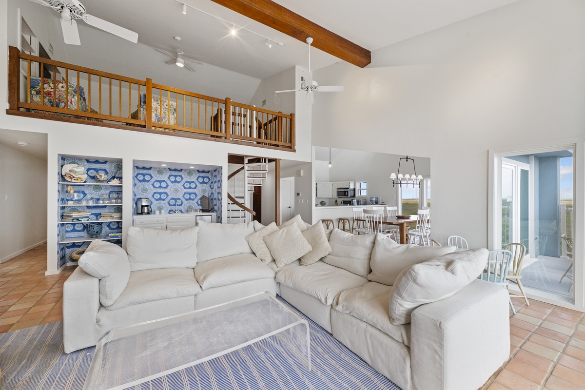 Relax in your spacious living area with soaring ceilings, exposed beams, and a cozy loft overlooking the open-concept design.