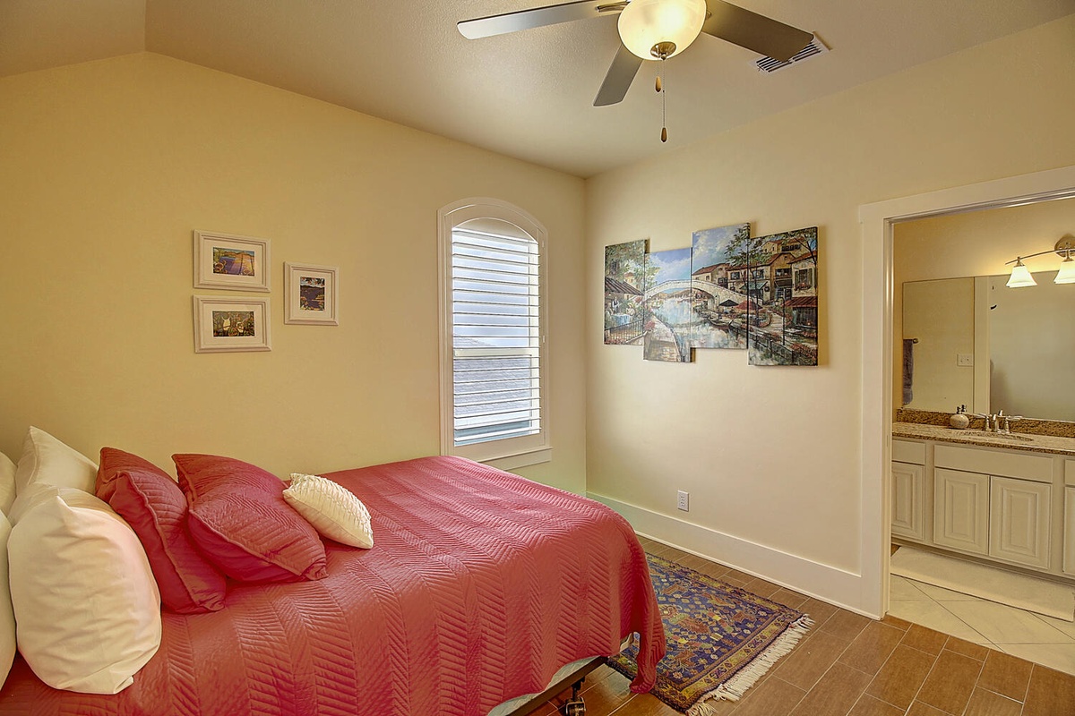 Your spacious bedroom offers a comfortable bed with vibrant linens, gentle ceiling fan, and an ensuite bathroom for convenience.