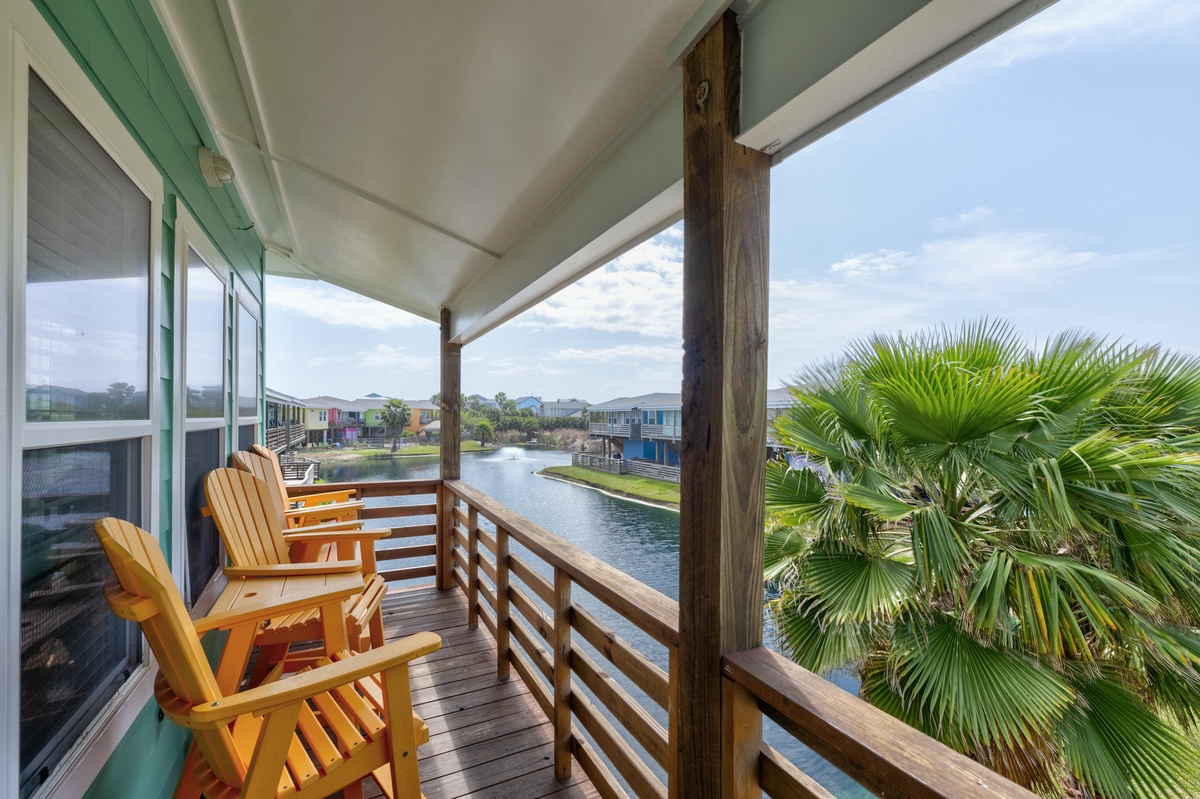 Step onto your private balcony and unwind in cheerful Adirondack chairs while soaking in serene waterfront views framed by swaying palms and coastal charm.