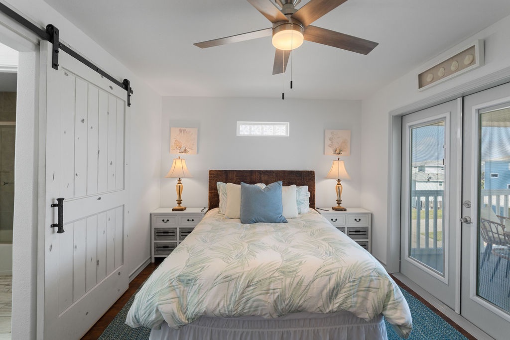 Your serene bedroom sanctuary features coastal bedding, warm lighting, and sliding doors to your private balcony for peaceful mornings.