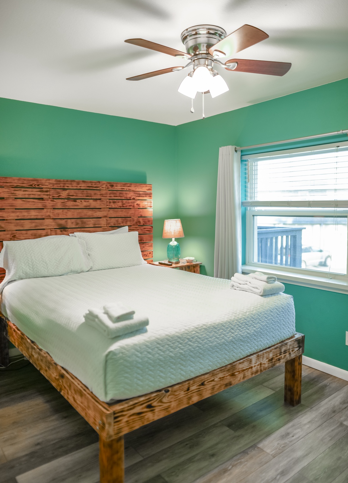 Unwind in your vibrant bedroom featuring rustic wood accents, soft linens, and a ceiling fan for perfect comfort.