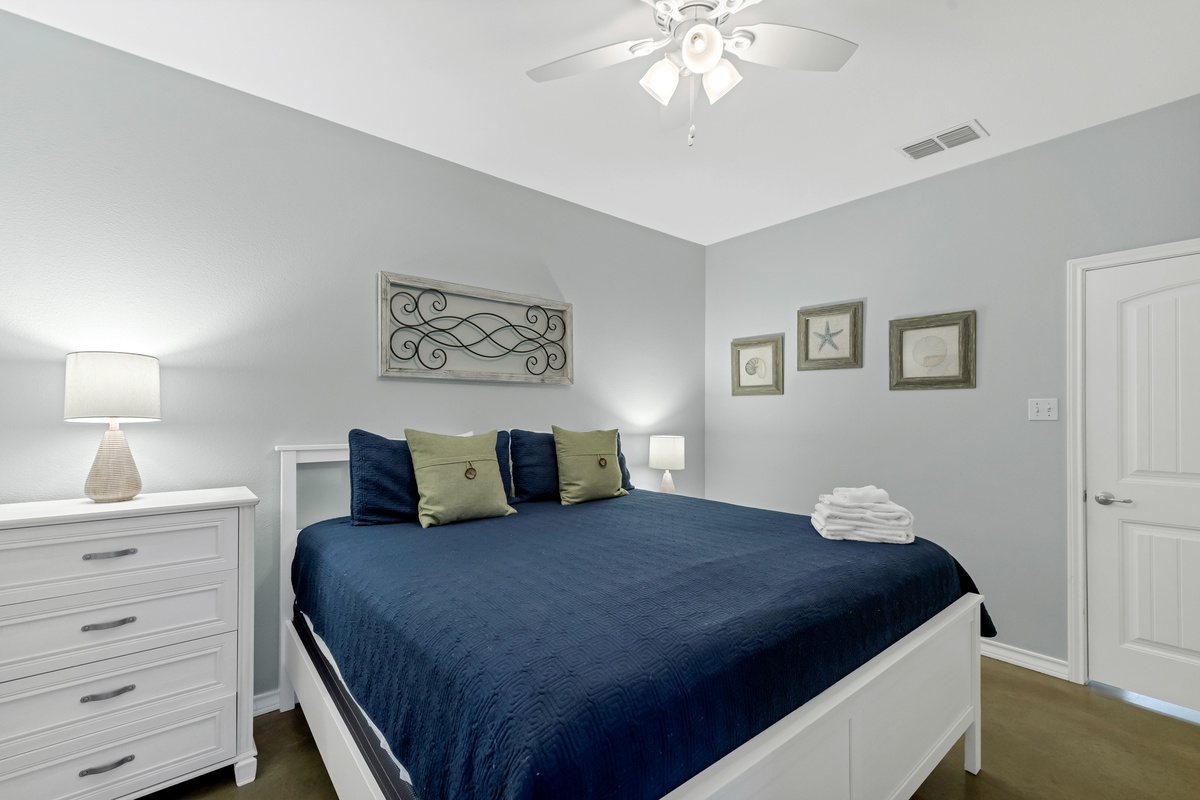 Relax in your serene bedroom with crisp white furnishings, soft blue bedding, and thoughtful touches like fresh towels waiting for you.