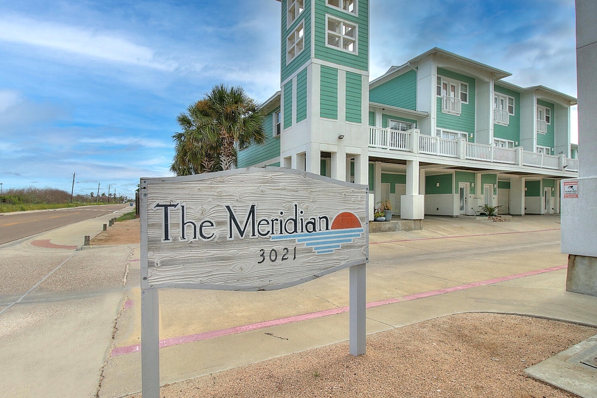 The Meridian property features distinctive green coastal architecture with modern townhomes and convenient street access for your arrival.