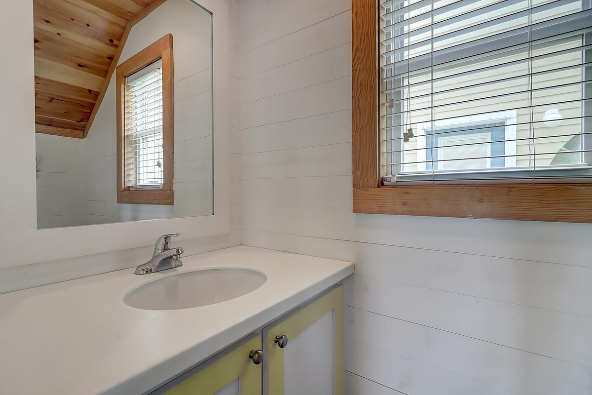 Refresh in your bright, cheerful bathroom featuring warm wood accents and natural light streaming through the window.