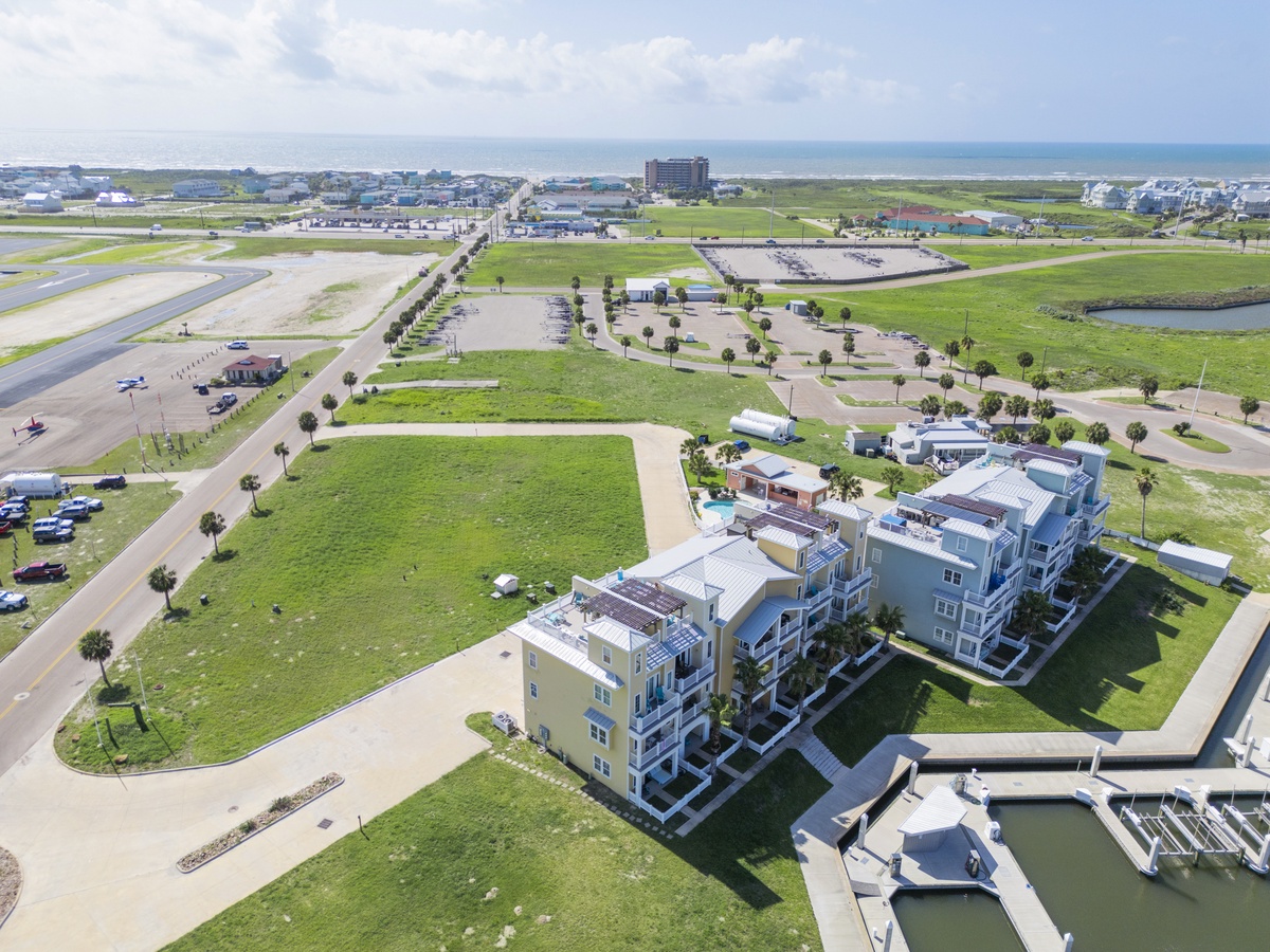 Aerial view showcases modern waterfront buildings near marina facilities and coastal access points in a peaceful community setting.