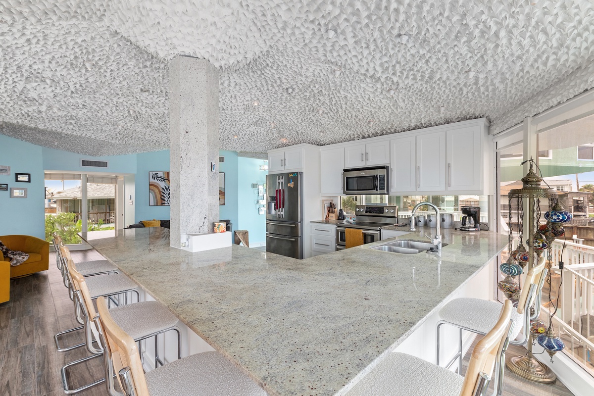Step into your modern kitchen featuring granite countertops and stainless steel appliances, perfect for preparing meals while enjoying ocean breezes.