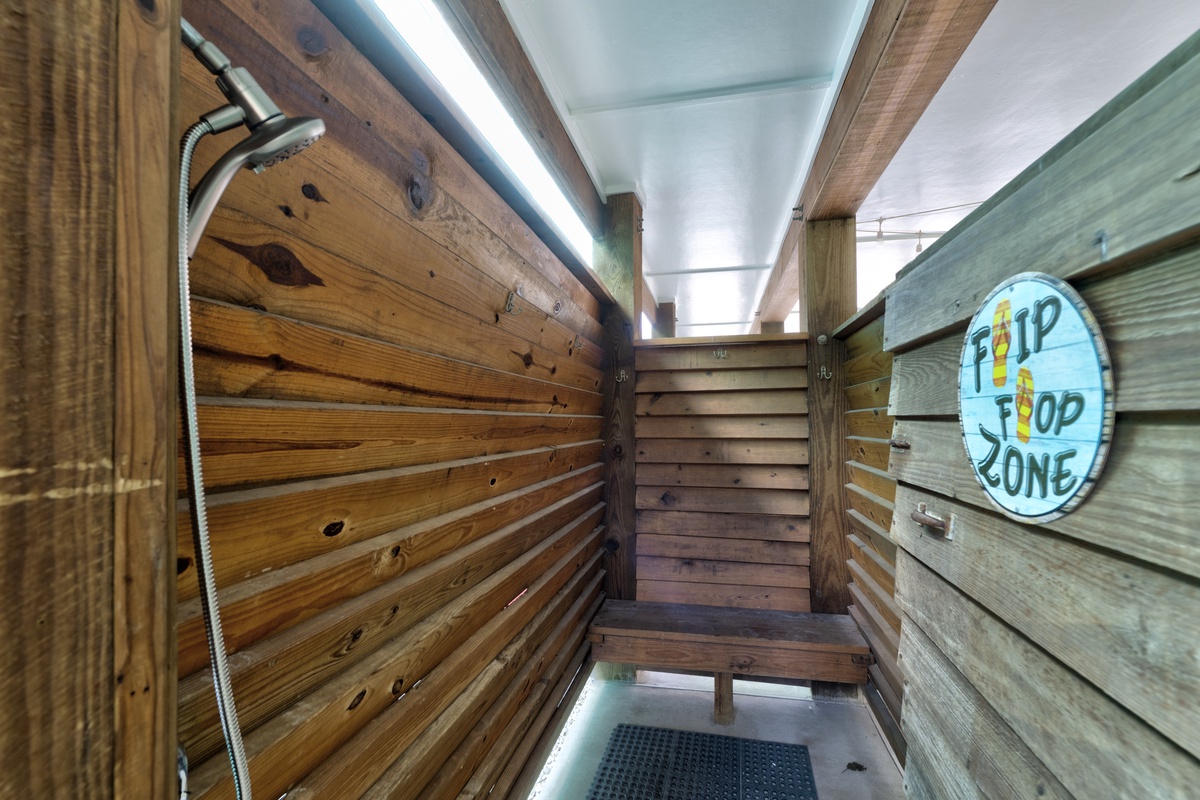 Your private outdoor shower awaits—rinse off sand under warm sun with rustic wood walls and coastal charm all around.