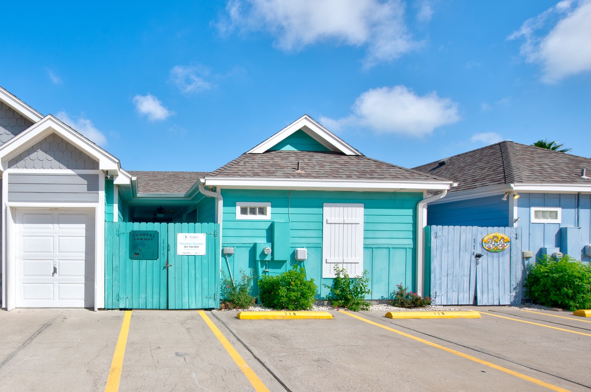 Charming turquoise beach cottage with bright coastal colors and convenient parking spaces for a perfect seaside getaway.