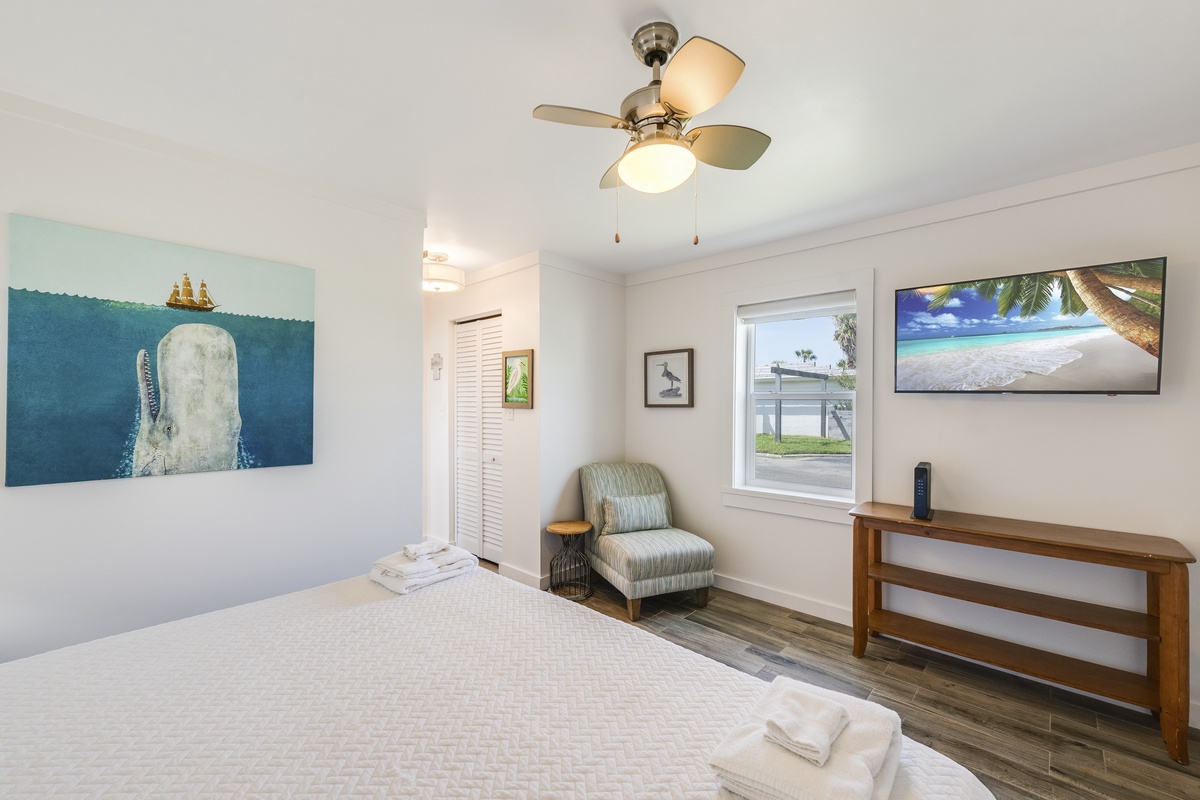Stretch out in this spacious primary bedroom with a cozy reading chair, Smart TV, and calming coastal touches designed for total relaxation.