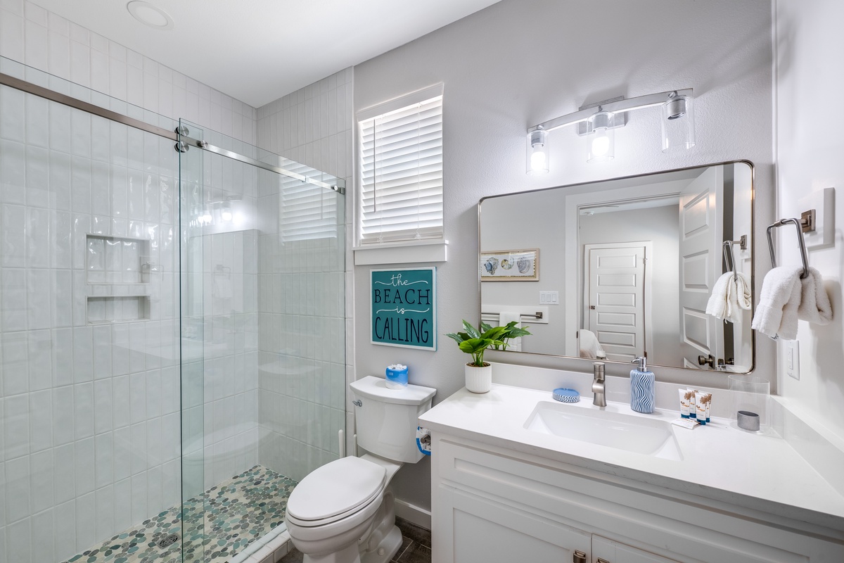 Refresh in your modern bathroom with rainfall shower, pristine vanity, and coastal touches that make morning routines feel like spa moments.