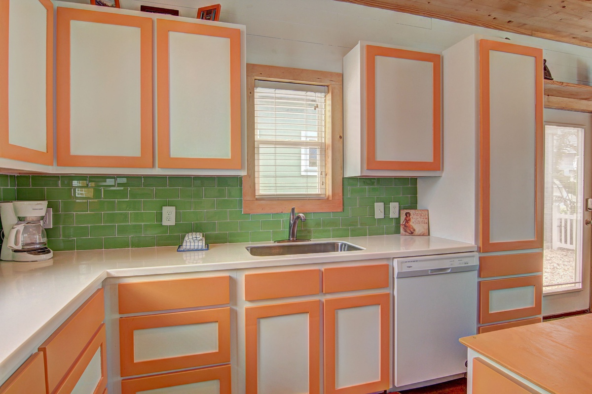 Your fully-equipped kitchen features vibrant orange and green accents, stainless steel appliances, and plenty of counter space for preparing meals during your stay.