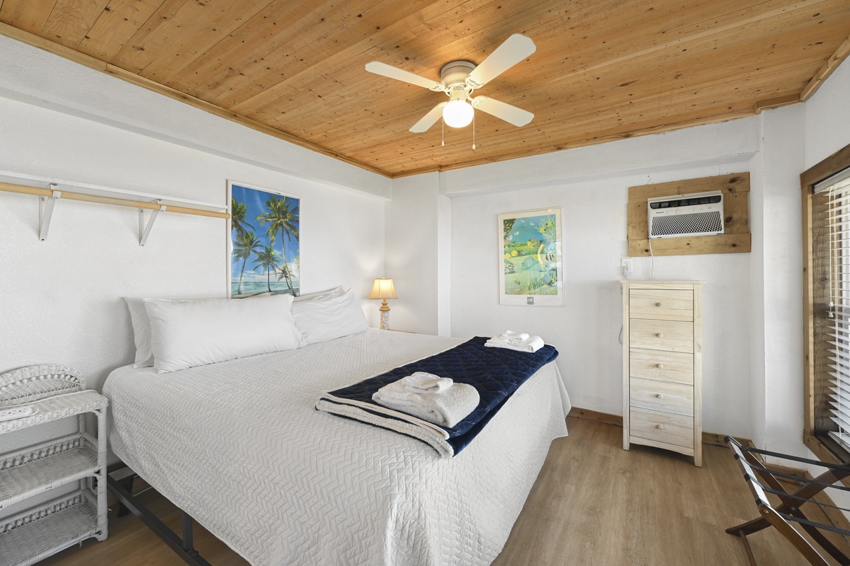 Picture yourself sinking into this plush bed beneath charming wood-paneled ceilings. Coastal artwork and fresh towels await your arrival in this bright, breezy retreat.
