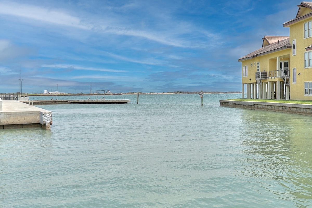 Waterfront property nestled along pristine turquoise waters with private marina access and charming yellow coastal architecture.