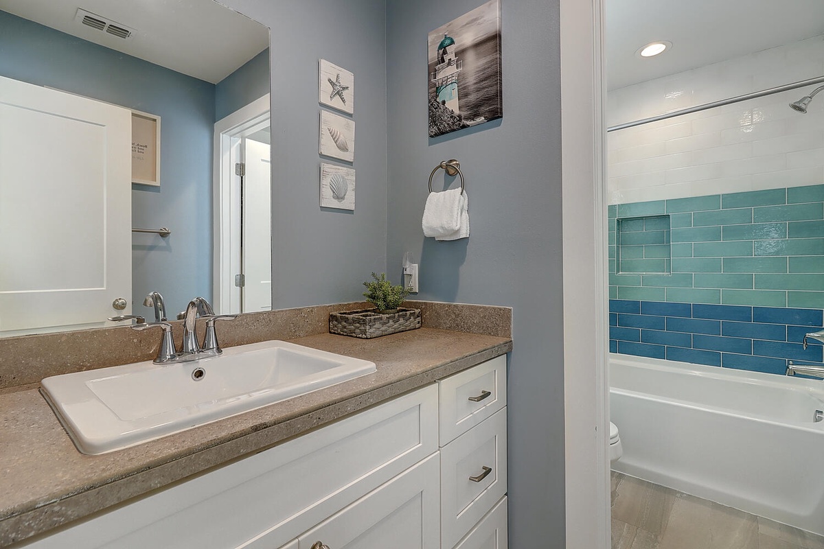 Refresh in your beautifully appointed bathroom with coastal charm, featuring elegant blue tiles and thoughtful seaside touches.