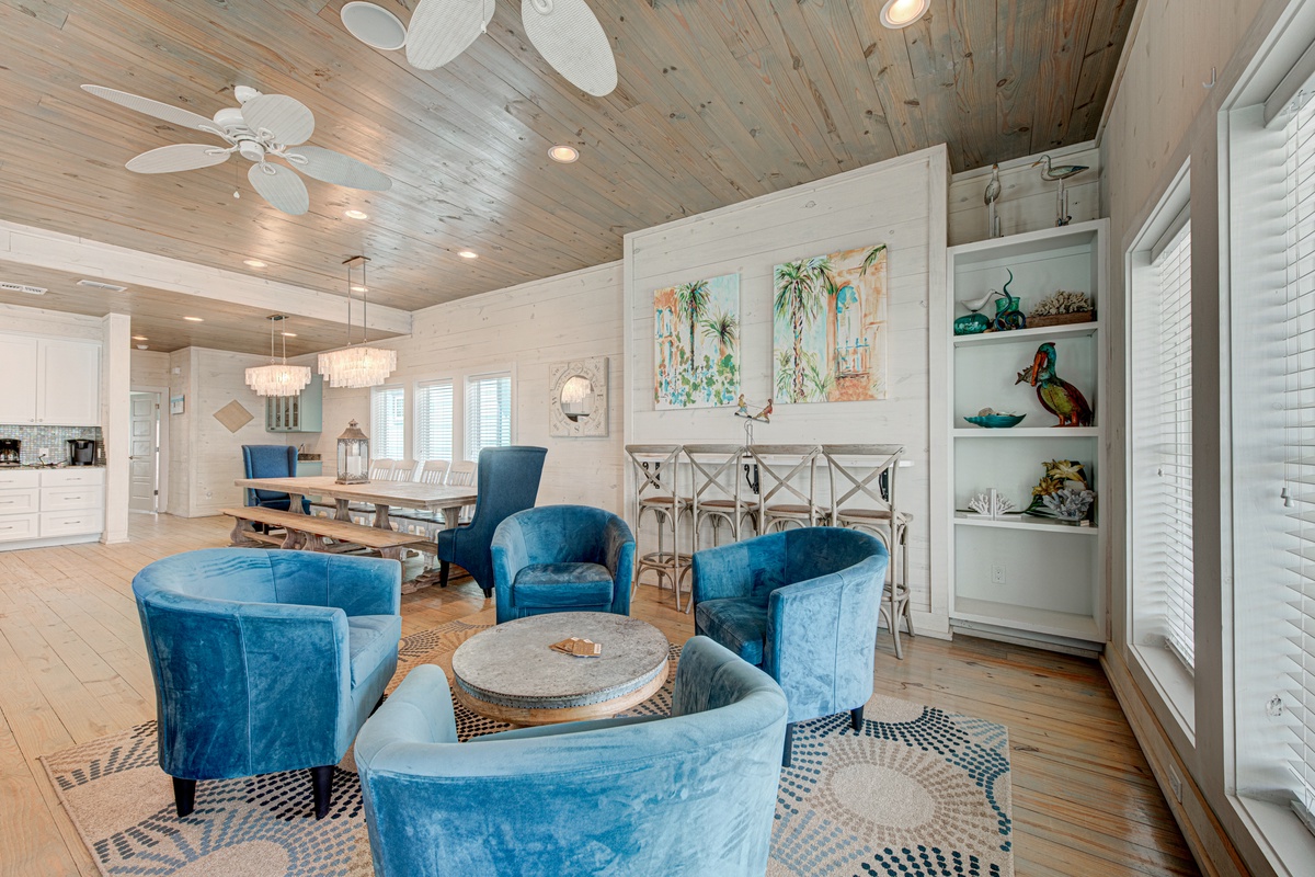 Unwind in this stunning living room with plush blue velvet seating, rustic wood ceilings, and coastal charm perfect for your relaxing getaway.