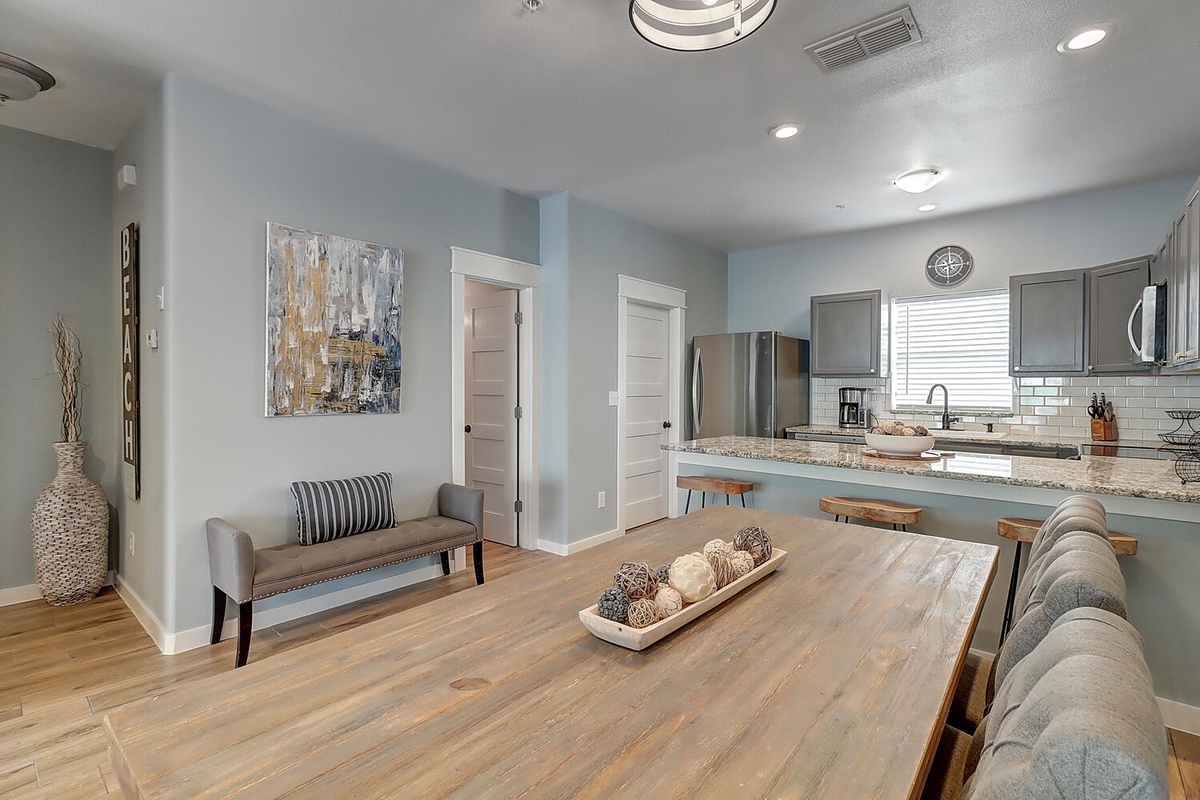 Your open kitchen flows seamlessly into the dining area, where a warm wood table invites memorable meals together.