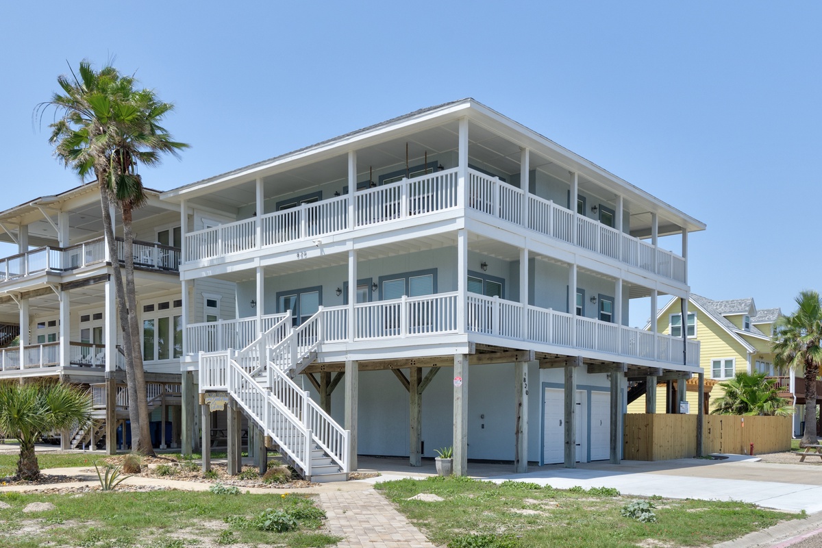 Modern beachside property featuring two-story coastal architecture with wraparound balconies and tropical landscaping in a peaceful residential setting.