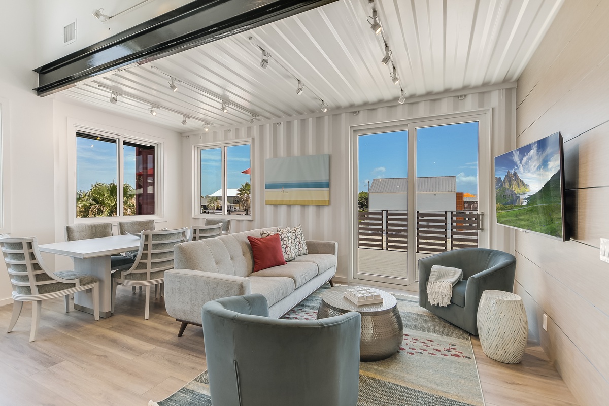 Unwind in your bright, modern living space featuring sleek furnishings, a wall-mounted TV, and windows that frame tropical views perfectly.