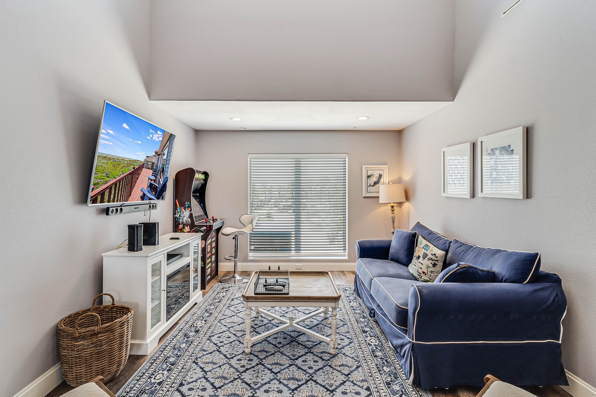 Cozy living room with plush navy sofa, modern entertainment center, and charming nautical touches perfect for relaxing after exploring.