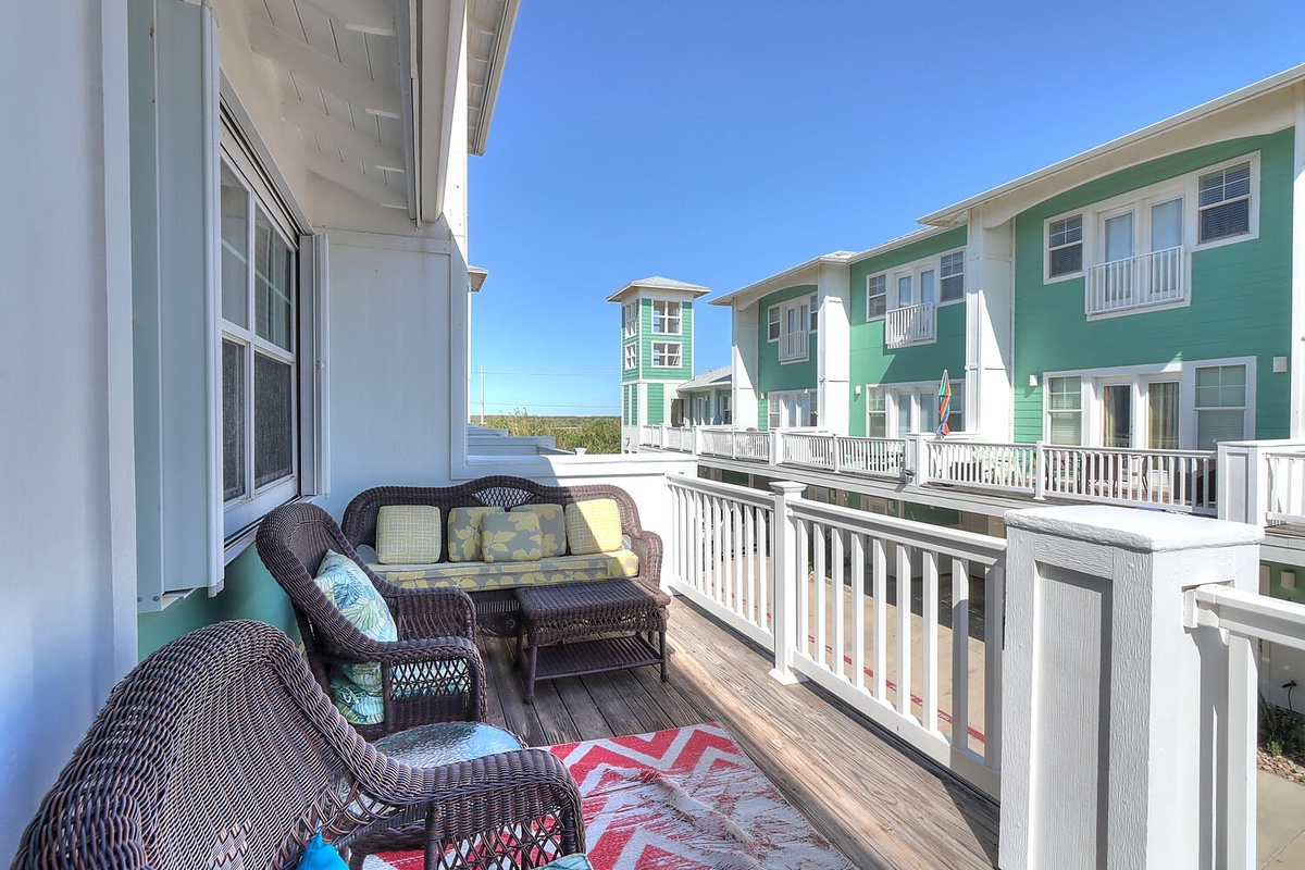 Relax on your private deck with wicker furniture and colorful cushions, overlooking the charming coastal community.