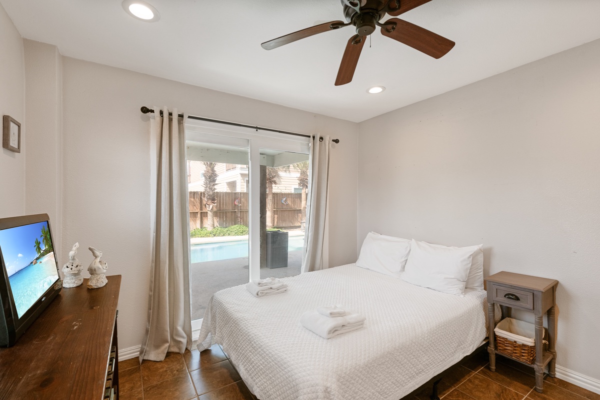 Unwind in your serene bedroom with pool views and modern comforts, including ceiling fan and entertainment system.