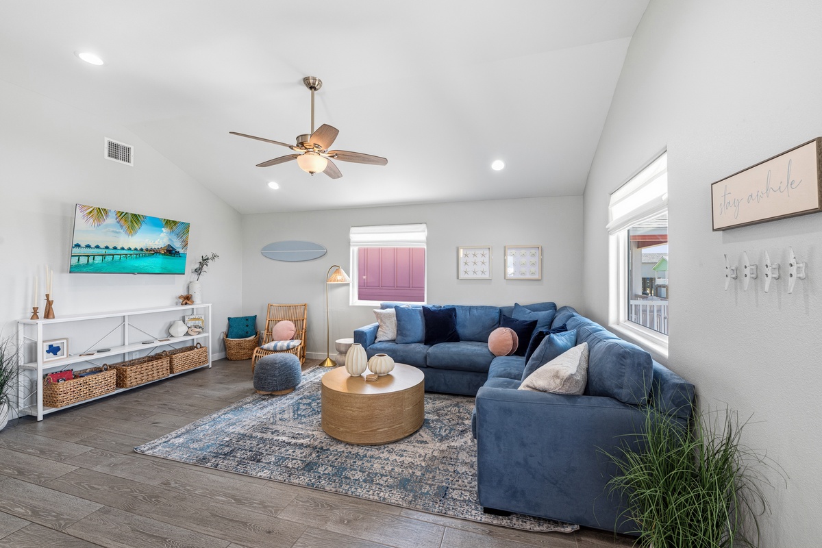 Sink into the plush blue sectional and relax in your bright, airy living room, where vaulted ceilings and coastal touches invite you to unwind in style.