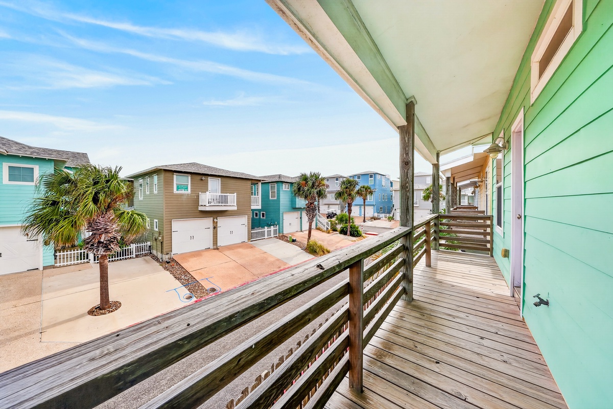 Coastal neighborhood with colorful beach homes and swaying palms visible from the property entrance.