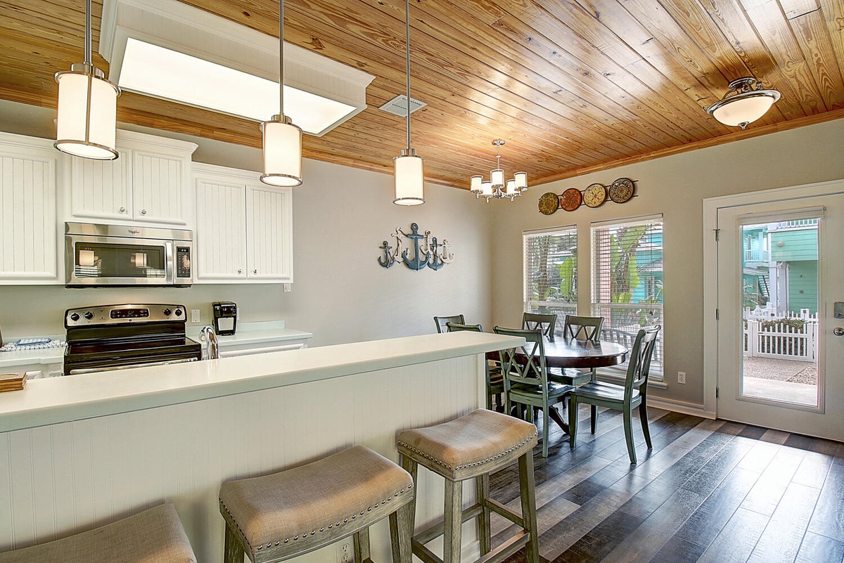 Gather around this coastal kitchen's breakfast bar for morning coffee while the wood ceiling adds warmth overhead.