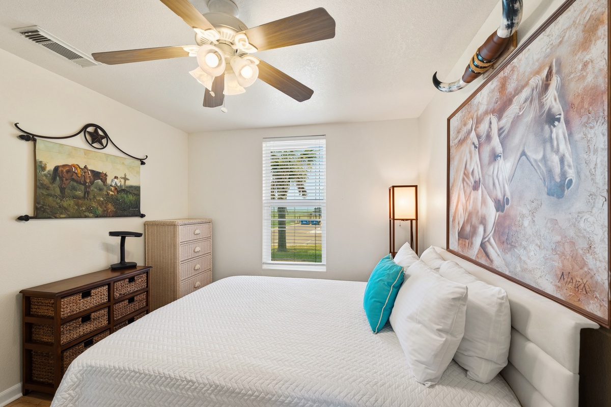 Sink into crisp white linens and let the ceiling fan's gentle breeze lull you into a peaceful night's rest in your cozy retreat.