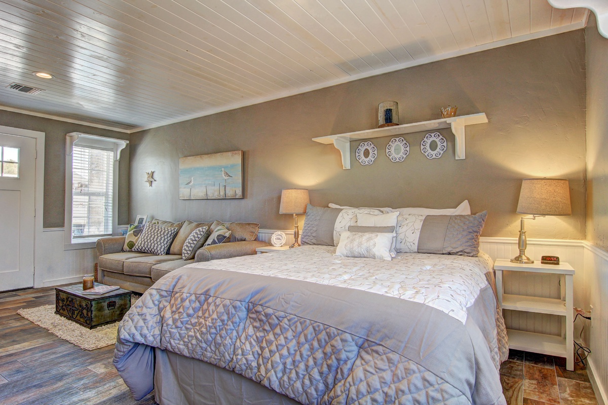 Unwind in your serene bedroom featuring a plush king bed, cozy seating area, and coastal charm with beautiful natural light.
