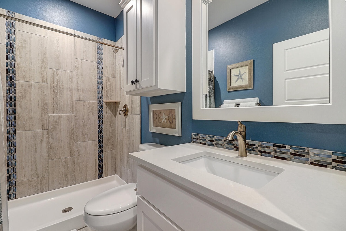 Refresh in your beautifully appointed bathroom with calming blue walls, elegant tile work, and a spacious walk-in shower.