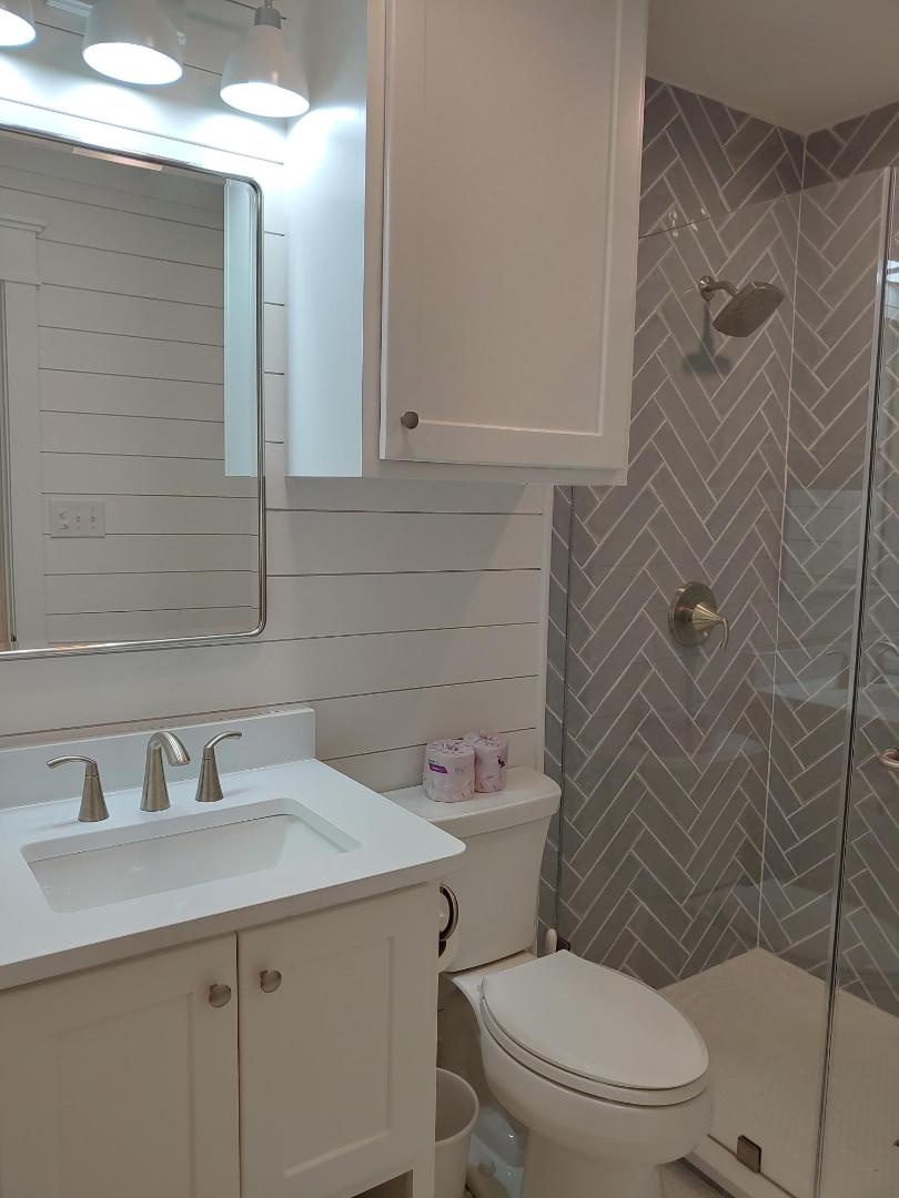 Refresh in your beautifully renovated bathroom featuring modern herringbone tile and crisp white shiplap walls.