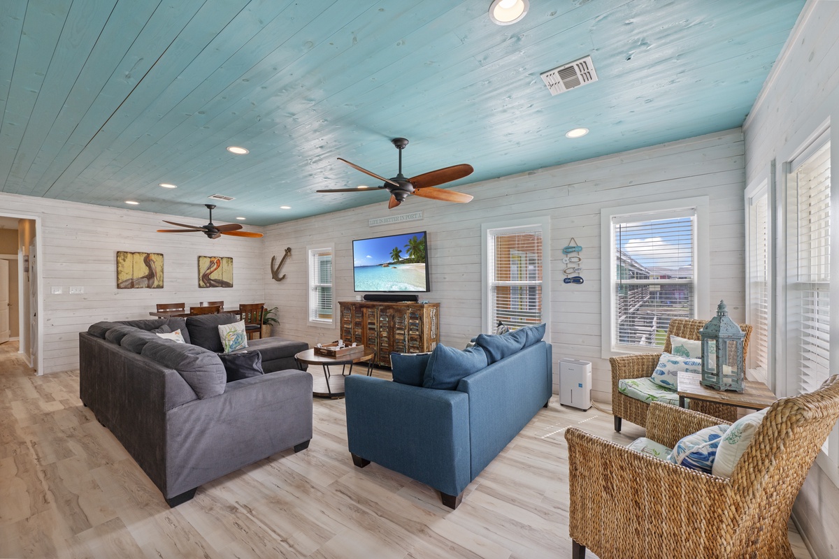 Relax into plush seating beneath coastal-blue ceilings and ceiling fans, where wicker accents and nautical touches create a breezy, inviting atmosphere for your vacation retreat.