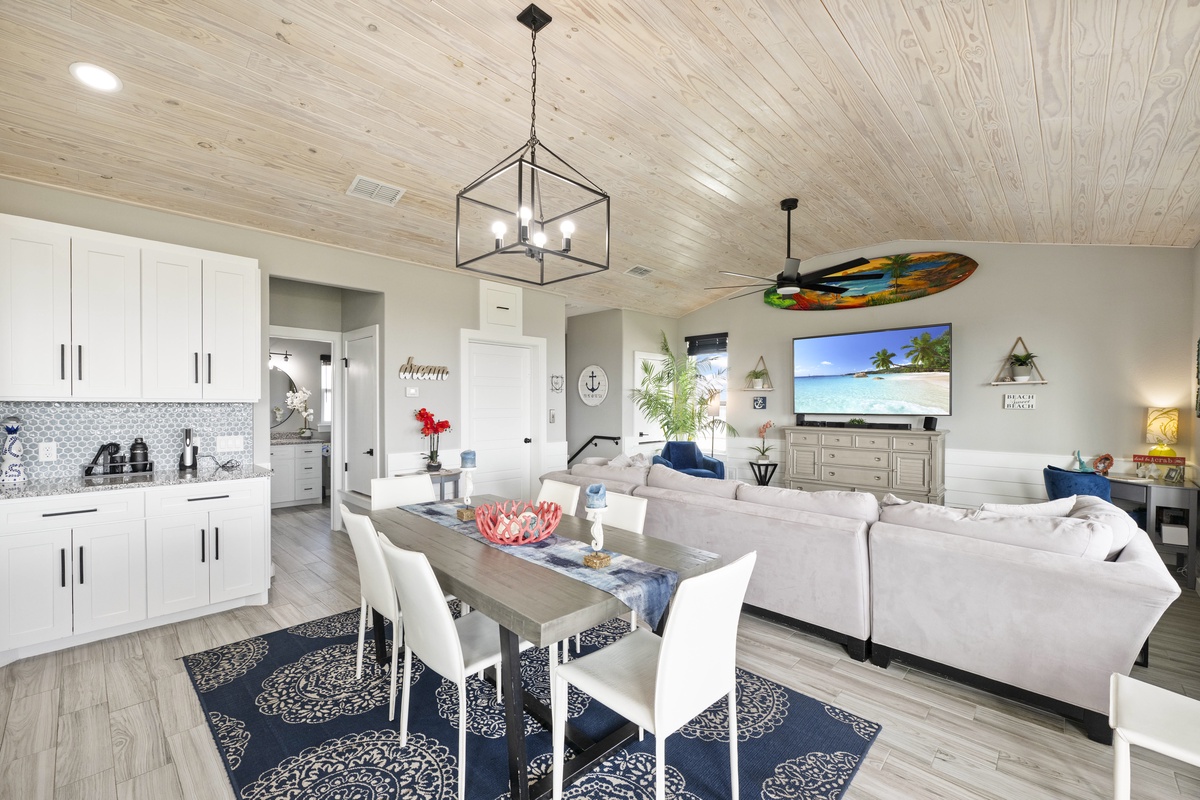 Relax in your stylish open-plan living space where coastal charm meets modern comfort, complete with a fully-equipped kitchen and cozy seating.